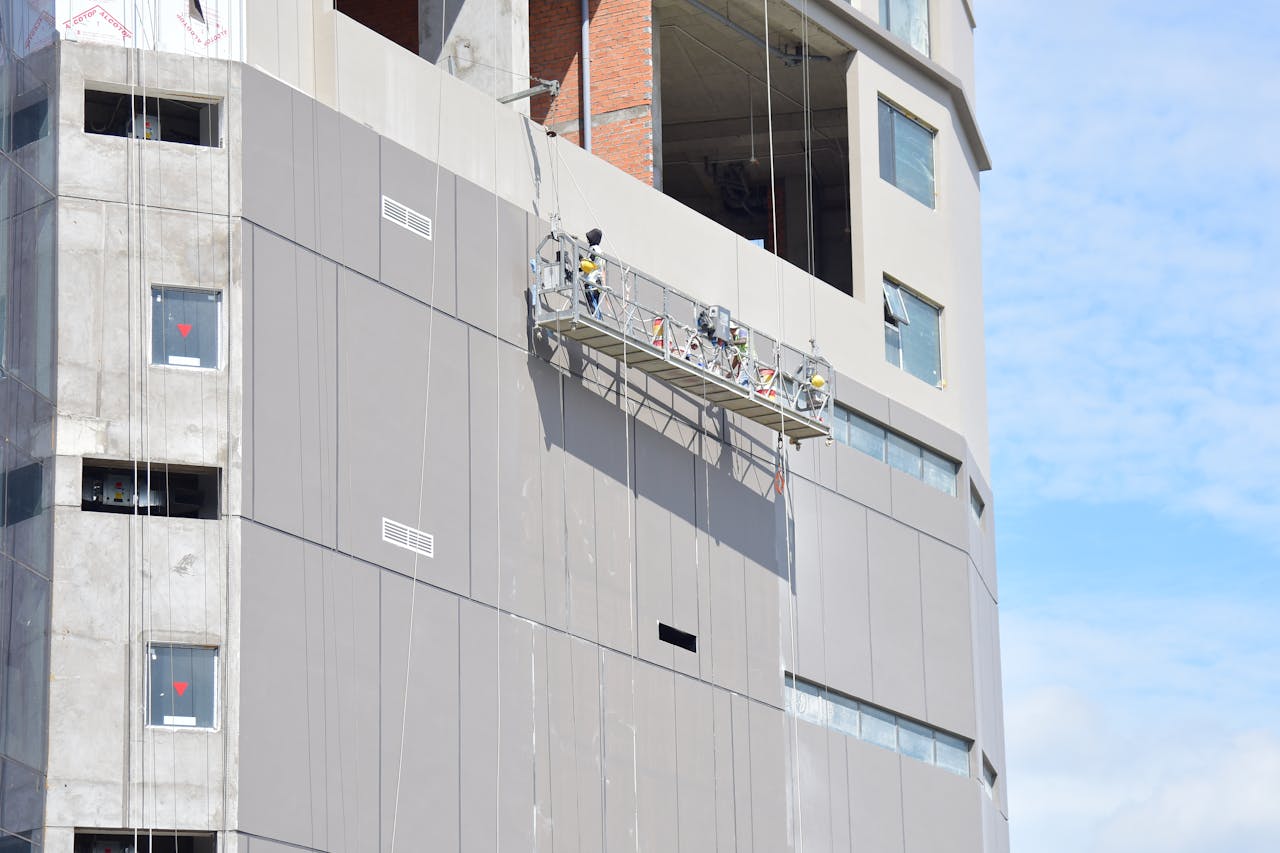 Workers on a suspended platform conducting maintenance on a high-rise building facade.